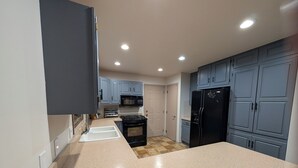 A kitchen with a stove, oven, sink, and black refrigerator.
