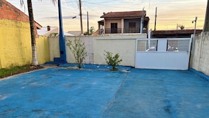 A rooftop with a blue surface, a small tree, and a building with a tiled roof in the background. - Casa em Ilha Comprida (Ilha Comprida)