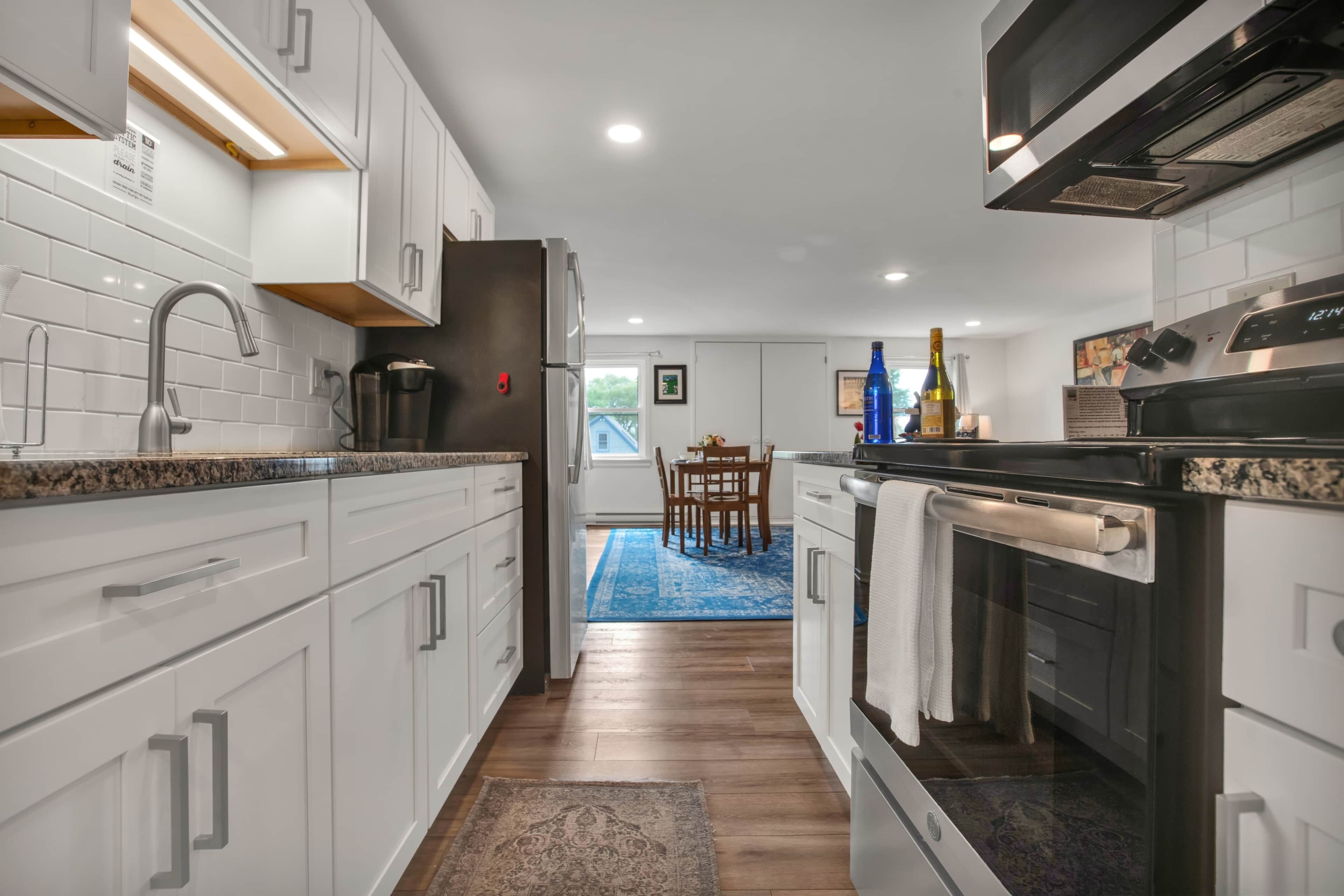 A modern kitchen with white cabinetry, a stainless steel refrigerator, and a built-in oven.