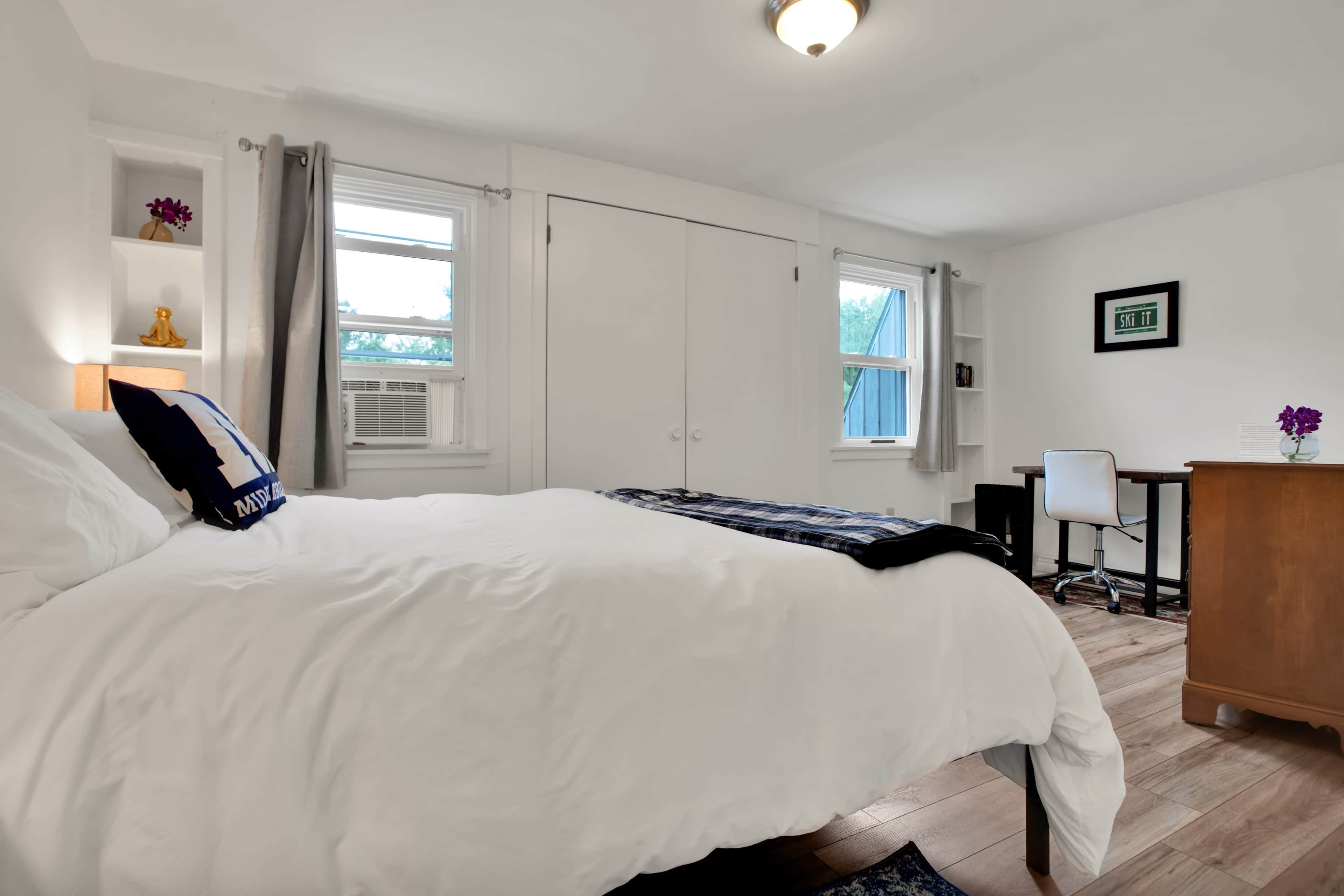 A bedroom with a large bed, a desk, and a chair.