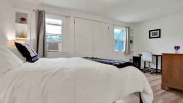 A bedroom with a large bed, a desk, and a chair.