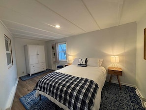 Un dormitorio con cama, cómoda, mesita de noche, ventana y puerta.