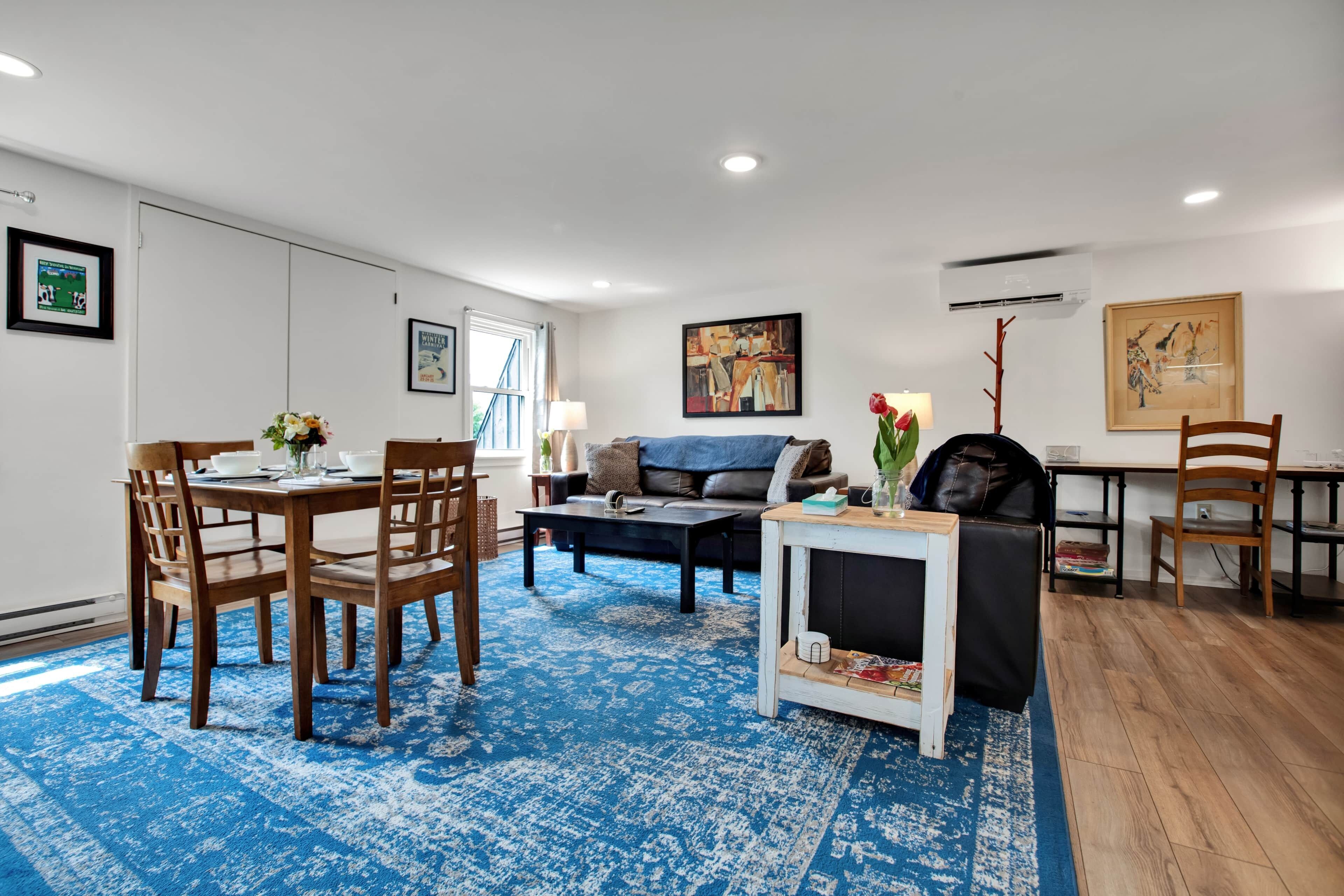 Un salon moderne comprenant un coin repas, un canapé, une table basse et un tapis.