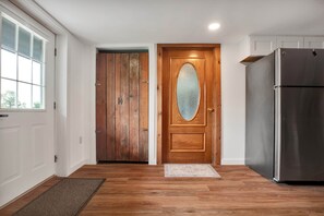A kitchen with wooden flooring, a refrigerator, and a double door with a frosted glass window. - Charming one bedroom just minutes to Middlebury! (New Haven)