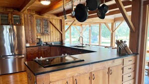 Una cocina con armarios de madera, un refrigerador de acero inoxidable y una isla grande con pileta.