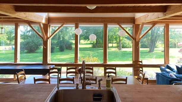 Un interior de madera con ventanas amplias, una mesa de comedor, sillas y un sofá.