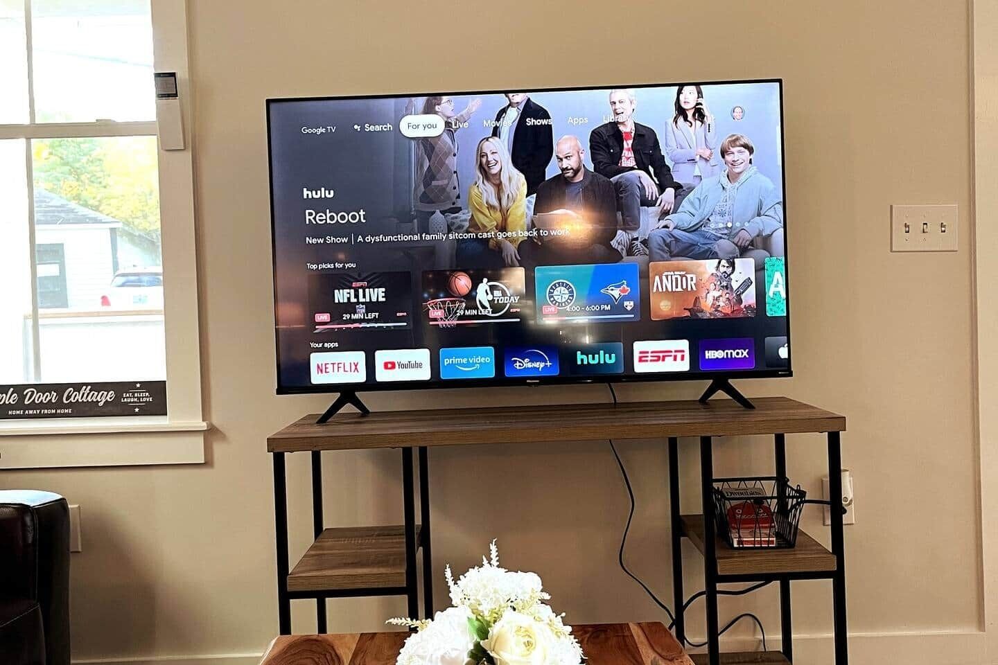 Ein Fernseher auf einem Holzboden, vor ihm eine Blumenkomposition.