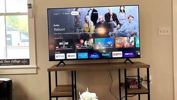 Ein Fernseher auf einem Holzboden, vor ihm eine Blumenkomposition.