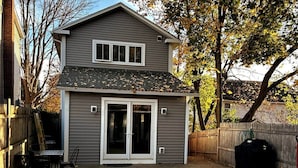 Une maison à deux étages avec une terrasse, une porte-fenêtre coulissante et un jardin clôturé.
