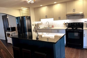 A modern kitchen with a central island, stainless steel appliances, and light-colored cabinetry.