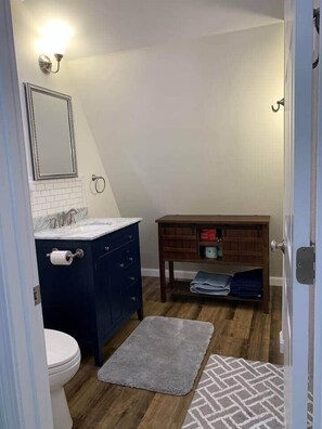 Ein Badezimmer mit Toilette, einem Waschbecken mit Handtuchhalter, einem Spiegel und einer Holzausstattung mit Handtuchstange.