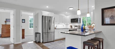 A modern kitchen with stainless steel appliances, a granite countertop, and pendant lighting.