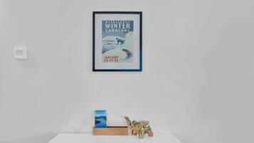Een lijst met een affiche van een wintercarnaval, een kaart en gids van Vermont, en een gouden olifantbeeldje op een witte plank.