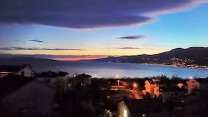 Une ville côtière au crépuscule, avec des maisons et une étendue d’eau.