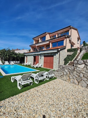 A two-story building with a swimming pool, lounge chairs, and a stone wall. - Villa Vrata Jadrana 1 (Rijeka)