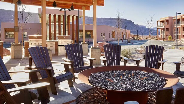 Un'area salotto esterna con poltrone Adirondack, un braciere e un barbecue.