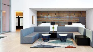 Una hall moderna con un divano componibile, due tavolini rotondi e un murale astratto dai colori vivaci.