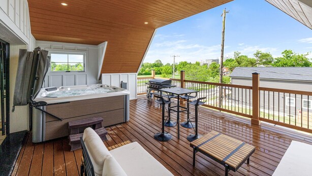 Un bain à remous avec une terrasse en bois, un barbecue et des meubles de jardin.