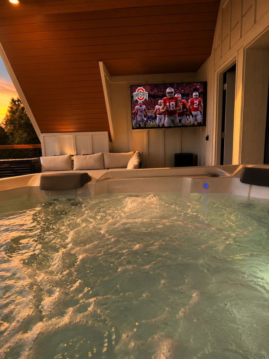 Ein Whirlpool mit Wasser, ein Fernseher, der ein Fußballspiel zeigt, und eine Holzbalkendecke.