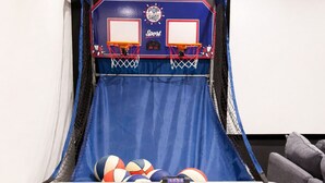 Un panier de basket avec un filet bleu, et un téléviseur fixé au mur juste au-dessus.