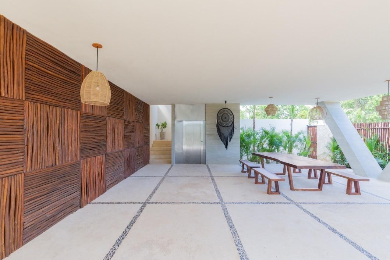 A covered outdoor area with a wooden wall, a staircase, a wall-mounted decorative item, and a long wooden table with benches.