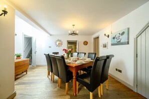A dining area with a wooden table, black chairs, a chandelier, and a painting on the wall. - Dog-Friendly 5-Bedroom Retreat with Hot Tub - Pass the Keys (Shrewsbury)