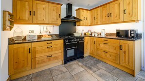 Een keuken met houten kastjes, een fornuis, oven en een magnetron.