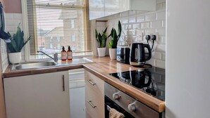 Een moderne keuken met een spoelbak, aanrecht, fornuis en potplanten.