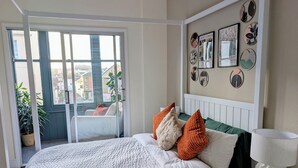 Een slaapkamer met een bed, kussens, een nachtkastje, een lamp en uitzicht door een schuifdeur.