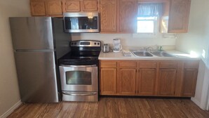 A compact kitchen with a refrigerator, stove, microwave, and a coffee maker. - Romantic Seclusion Lake Norfork Cottage 10 w/Jacuzzi at Teal Point Resort w/private lake access (Mountain Home)