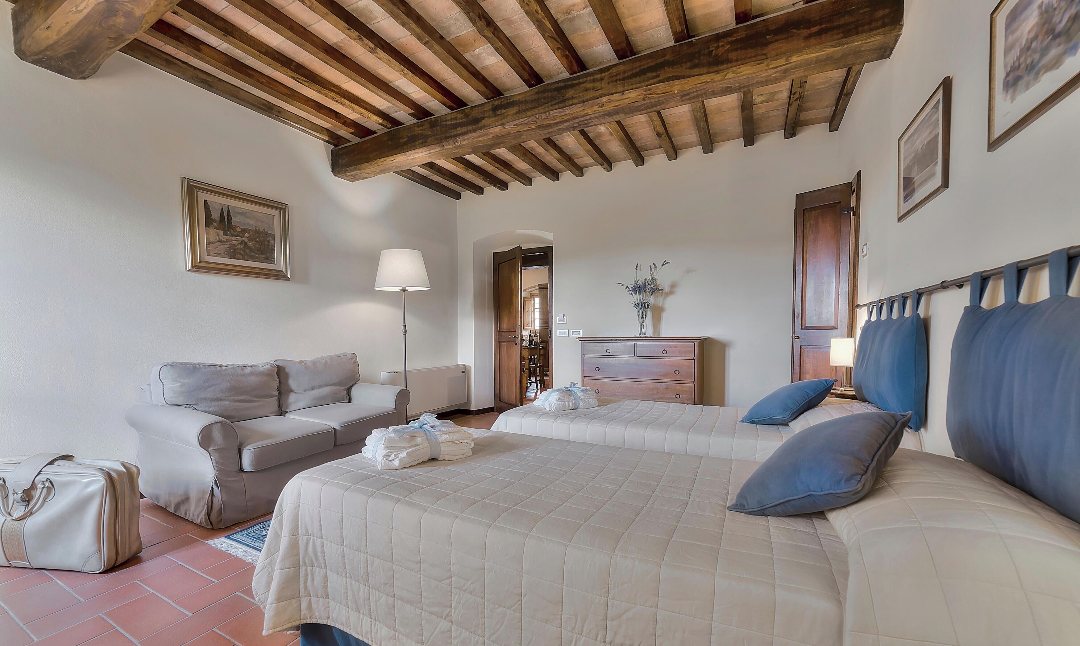 A bedroom with a bed, a sofa, a dresser, and a lamp.