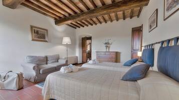 A bedroom with a bed, a sofa, a dresser, and a lamp.