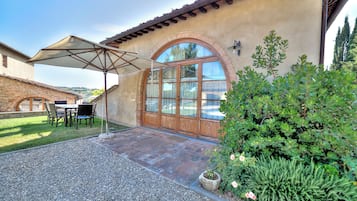 Un patio con tavolo e sedie, un ombrellone e un muro in pietra.