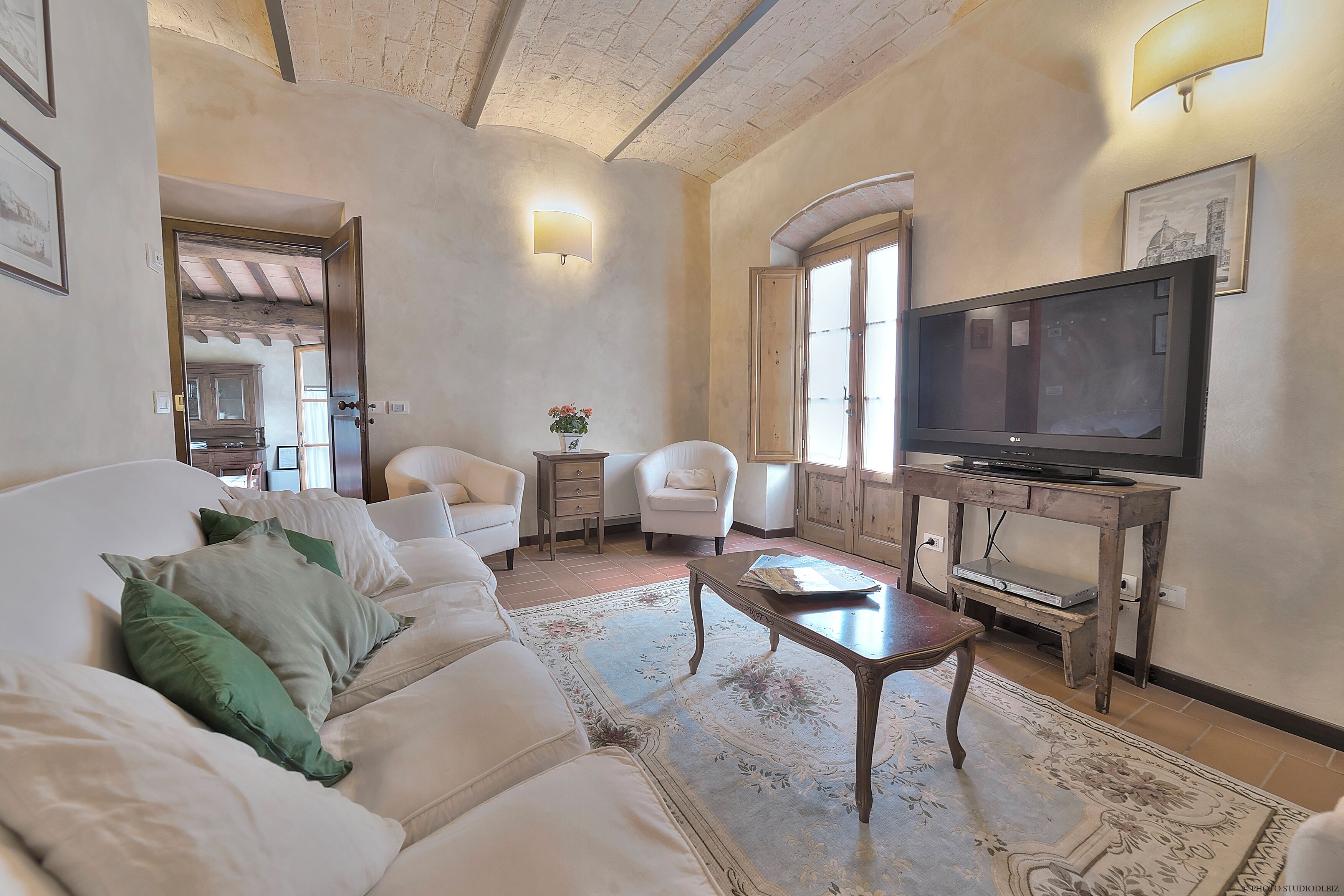 A living room with a sofa, armchairs, a coffee table, a television, and a fireplace.