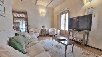 A living room with a sofa, armchairs, a coffee table, a television, and a fireplace.