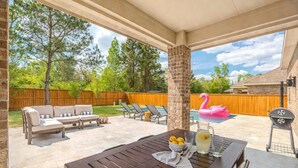 Une terrasse extérieure avec une table en bois, des chaises longues et un barbecue.