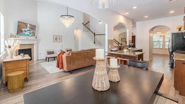 Un salon spacieux avec une cheminée, un coin repas avec une grande table et une cuisine équipée d’un réfrigérateur.