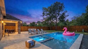Un jardin avec une piscine, des chaises longues et un flotteur en forme de flamant rose.