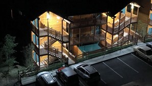 Un edificio a più piani con balconi e scale, circondato da automobili parcheggiate.