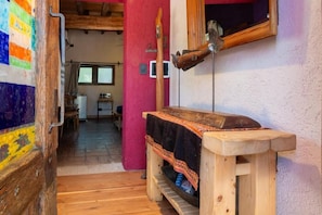 Een rustieke houten bank met een deken, een houten deur en een spiegel aan de muur.