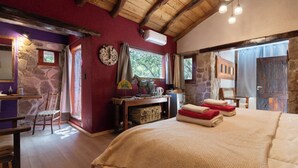 A room with a bed, a table, a chair, a fireplace, and a stone wall.