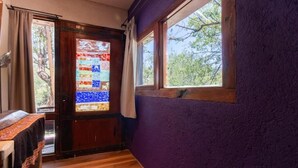 Ein Zimmer mit Holztür, Fenster und einer violetten Wand.