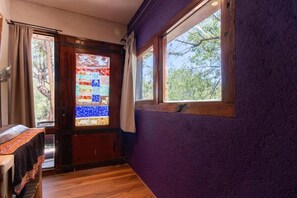 Ein Zimmer mit HolztĂŒr, Fenster und einer violetten Wand.