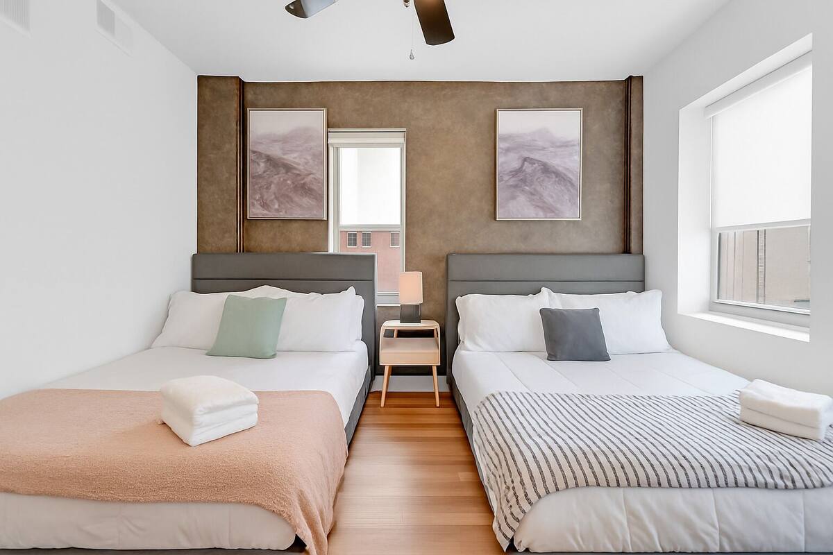 A modern hotel room with two beds, a nightstand, and artwork on the walls.
