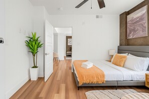 Une chambre à coucher moderne avec un lit, une table de chevet, une lampe et un grand tableau au mur.