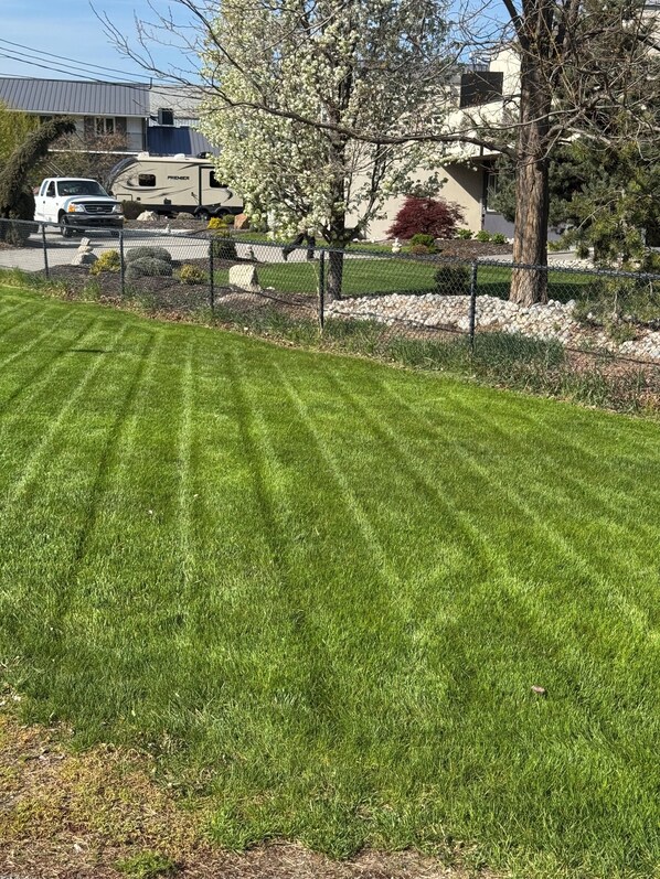 A well-maintained lawn with a parked camper and a house in the background. - Skaha Lake Airport Inn & Suites (Penticton)