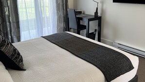 Ett hotellrum med en säng, ett skrivbord, en stol och en tv på väggen.