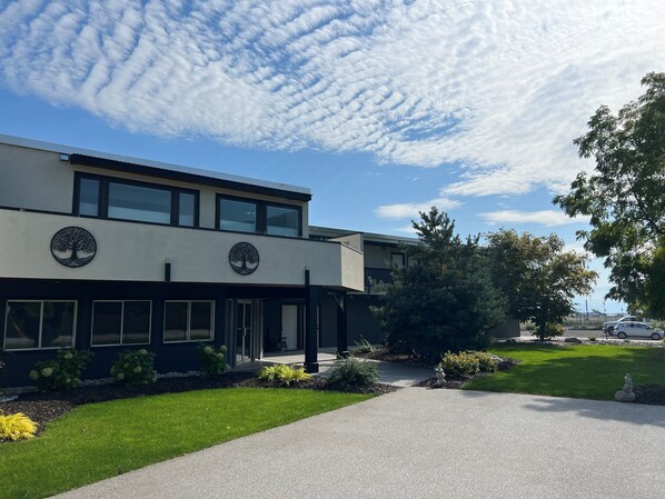 A modern building with a tree logo, a paved driveway, and well-maintained landscaping. - Skaha Lake Airport Inn & Suites (Penticton)