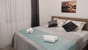 Una habitación de hotel con una cama, un cuadro y una ventana con cortinas.