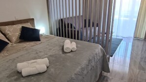 A hotel room with a bed, pillows, rolled towels, a nightstand, and a view through a window. - Dalmatia Apartments-Studio Apartment with Balcony 3a (Drage)